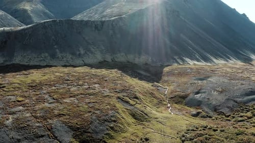 Drone flight toward rugged mountains over old volcanic landscape of Iceland