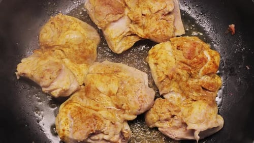 Chicken Thighs Simmering in Oil in Pan