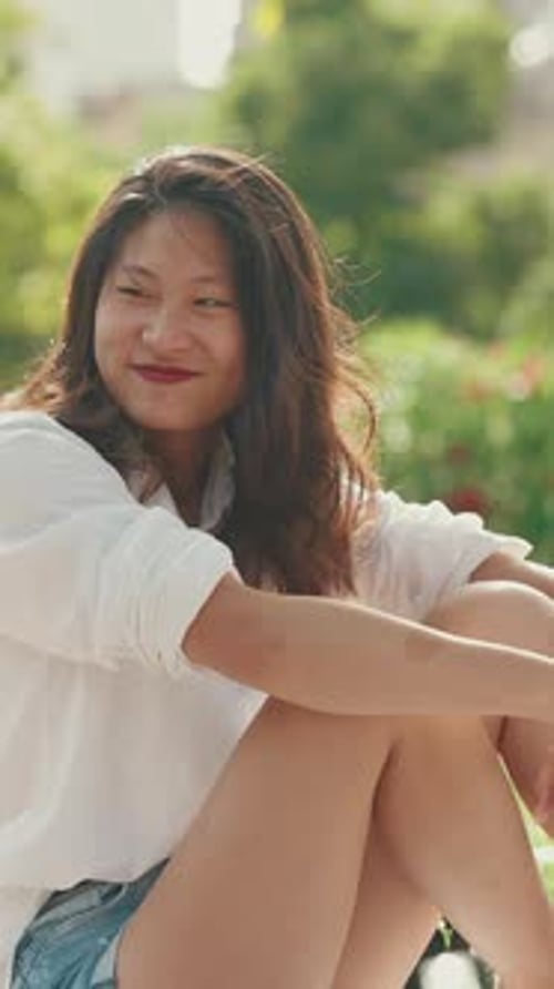 Close-up, young woman sitting in park having picnic, talking with friends