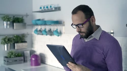 Man with Tablet and Phone in Bright Kitchen