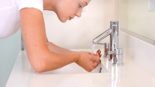 Woman Washing Her Face in a Modern Bathroom