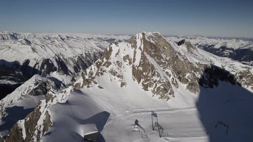 Vista panorámica aérea del soleado y nevado pico de la montaña con pista de esquí y cadena montañosa