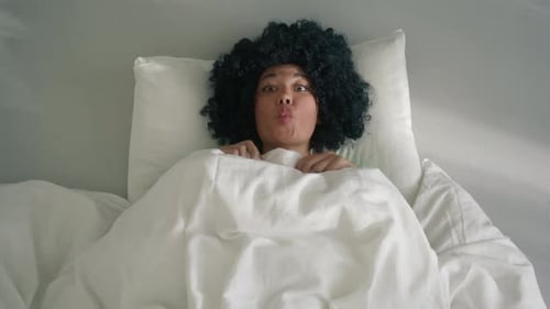 Jeune fille afro-américaine loufoque faisant des grimaces en étant stupide allongée dans son lit