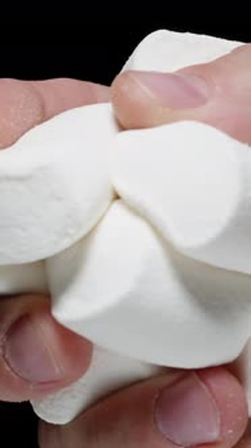 Vertical video. Hand Greedily Squeezes Sugar Marshmallows, But Soon Pours Them Out. Slow Motion