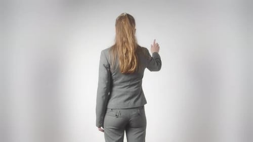 Rear View a Woman in a Business Suit on a White Background Makes Hand Gestures As She Uses a