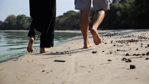Bare Feet of Couple Stepping Together Along Sand Beach at Coastline Male and Female Legs of Pair