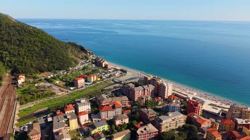 Aerial view of a coastal town in Italy with beach, mountains, and sunny weather
