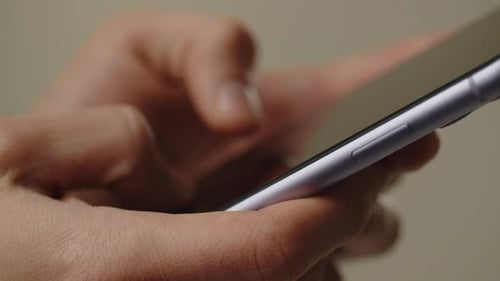 Cropped View of a Man Using His Smartphone A Man Holds a Smartphone in His Hands and Types a Message