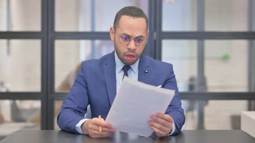 Businessman Reviewing Documents at His Desk