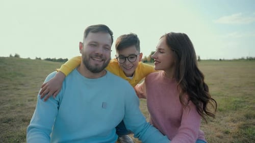 Smiling Family Embraces in Sunny Field