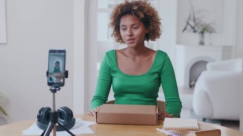Young Woman Recording Video at Home Opening Box