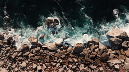 Drone View of Waves Crashing on Rocky Boulder Beach. Static Long Shot - Medium. Power, Energy Concep