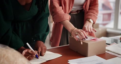 Women Packing Boxes and Making Notes at Desk