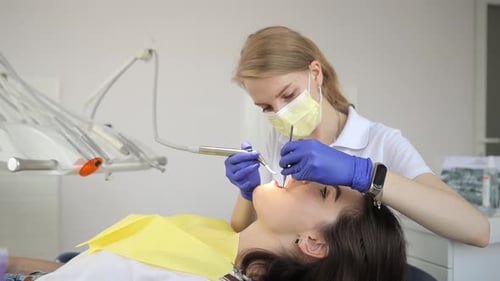 A Woman is Getting Her Teeth Examined By a Dentist in a Dental Office