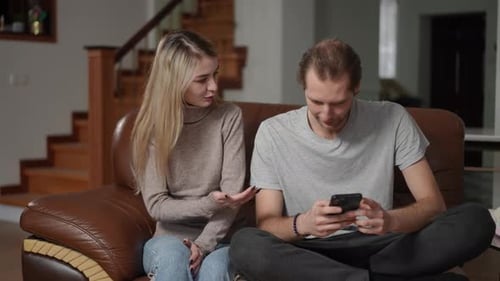 Wife Arguing with Her Husband While He is Focused on His Phone