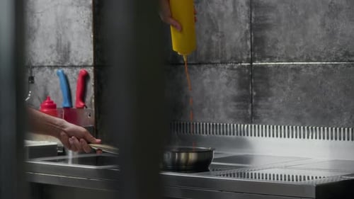 Anonymous Chef Adding Sauce to Frying Pan in Restaurant Kitchen