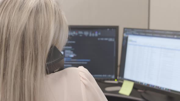 Businesswoman talking on the phone and typing an email in her office ...