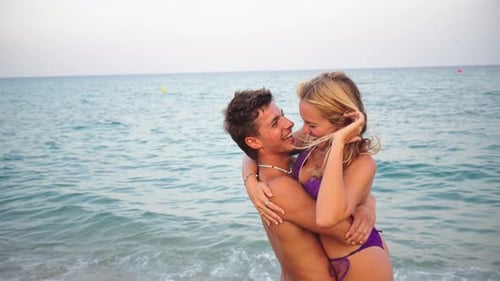 Joyful Couple Embracing at the Beach Under a Warm Sun During a Beautiful Summer Vacation Together