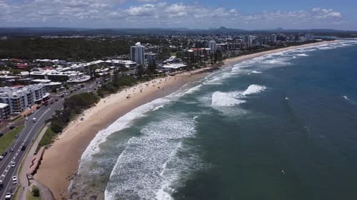Flying over a beautiful beach in Australia with seaside road and apartments.