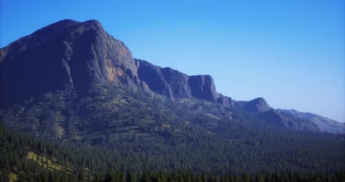 Majestic Mountain Range Under Clear Blue Sky with Green Forest Below