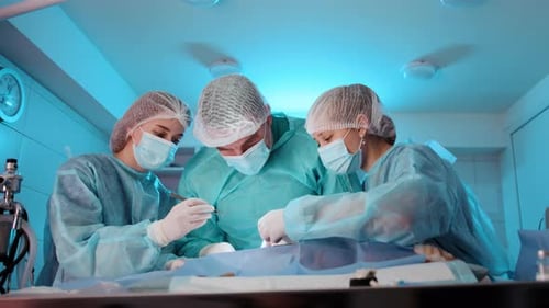 The Doctor is Being Assisted By Two Nurses During the Operation Procedure