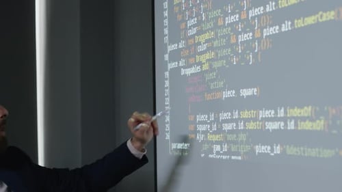 Male Programming Teacher Pointing to Variables in Code on Projector Screen