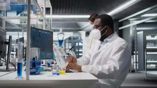 Forscher mit medizinischer Maske im sterilen Labor am Computer