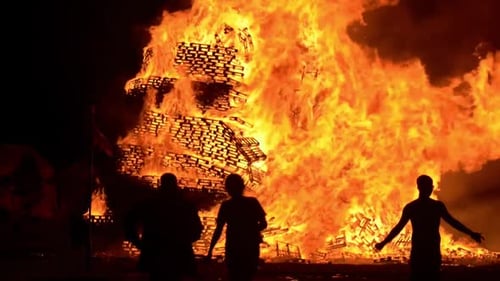 A huge celebration bonfire in Belfast. Bonfire collapses. People watch on and celebrate by dancing a