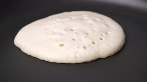 Golden Pancake Cooking on a Skillet being Flipped