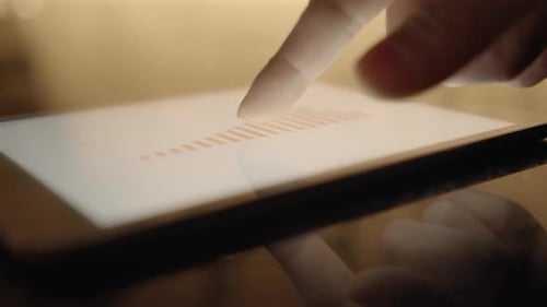 Hand Interacts With Business Data on Tablet Screen