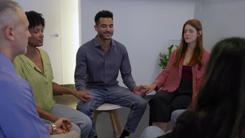 Diverse Group Holding Hands with Eyes Closed While Praying for Support