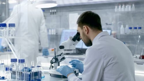 Man Using Microscope in Bright Laboratory Setting