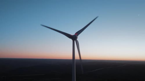 Close up view of large powerful wind turbine on top of the mountain at night. Green energy.