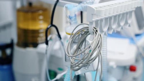 Folded wire from the medical equipment hanging in the ward. Lung ventilator machine at backdrop.