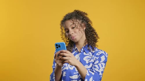 Smiling Woman Using Phone Against Yellow Background