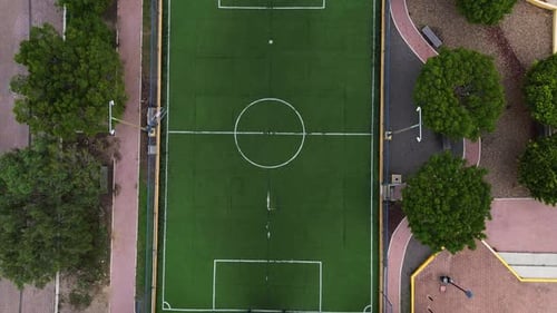 Drone view of an empty synthetic grass soccer field in the center of a park