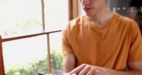 Young Man Uses Tablet Near Bright Window
