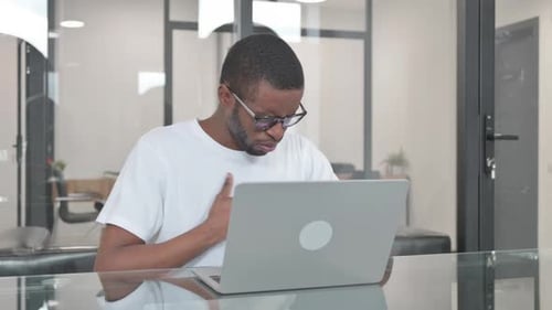 Coughing Young African Man Using Laptop in Office