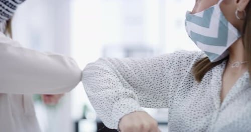 Séquence vidéo 4k de deux femmes d'affaires portant des masques et se cognant les coudes dans un bureau moderne