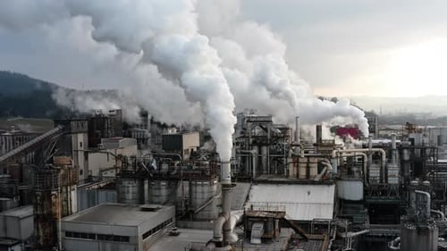 Industrial factory with smokestacks releasing thick white emissions into the sky