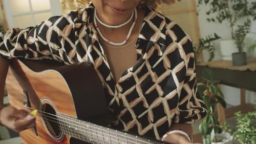 Woman Plays Guitar at Home in Sunny Room