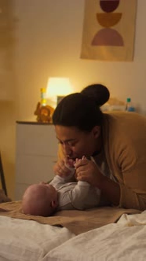 Fröhliche hispanische Mutter spielt zu Hause mit Baby mit Rassel