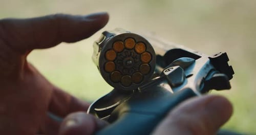 Closeup View of Loaded Revolver Cylinder Held in Hands at Shooting Range Outdoors