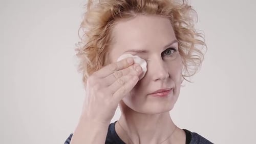 A woman erase face makeup eyeliner with cleaner cotton and makeup remover