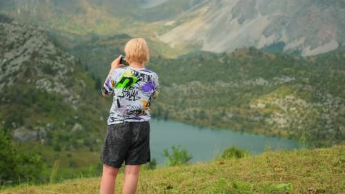 Tourist shoots on phone scenic views, make video grandiose mountain landscape with lake