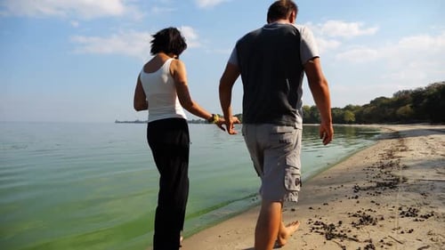 Couple Holding Hands of Each Other and Walking at Coast Happy Pair Going Along Seashore at Sunny Day
