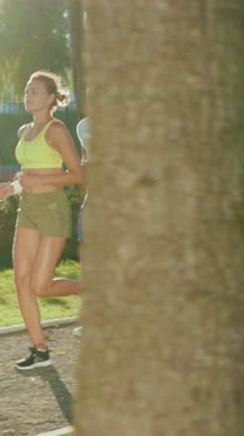 Energetic Individuals Joyfully Jogging in a Sunny Park Promoting a Lively Atmosphere