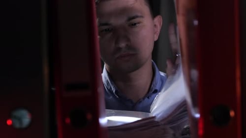 Man with Flashlight Examines Files in Office