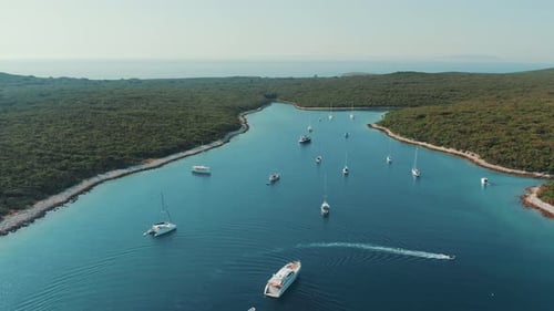 Aerial drone video of picturesque island bay with crystal clear water visited by yachts and sailboat