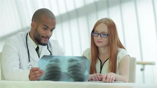 Doctor Reviews X-ray with Patient in Modern Office